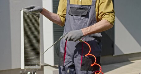 Plumber using compressed air to clean a dirty HEPA filter.