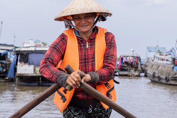 Photo of a Vietnamese woman navigating through the floating market in the mekong delta