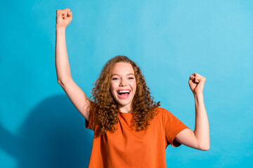 Photo of young successful red haired girl in orange t shirt raised fists up celebrating boyfriend...