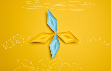 Four paper boats stand at the same departure point, but different trajectories are drawn. The concept of uniqueness