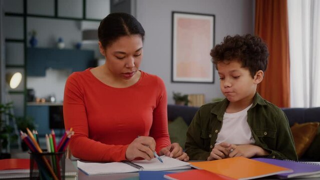 African American family at home mother woman female private teacher study education check homework task dissatisfied confused talk to little boy child schoolboy kid son bad result mistake studying
