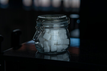 Glass sugar bowl with cup of cobi sugar on a dark background.
