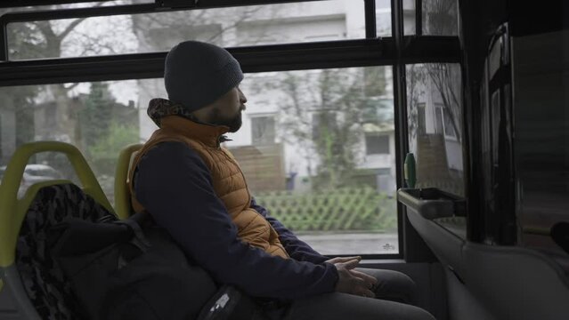 Male passenger travels on Berlin bus in Germany in winter in overcast weather. Municipal bus BVG, Berliner Verkehrsbetriebe view from inside. Thema Offentlicher Verkehr in Deutschland