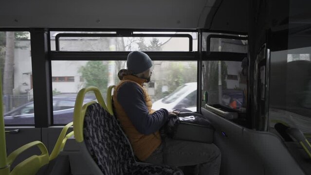 Male passenger travels on Berlin bus in Germany in winter in overcast weather. Municipal bus BVG, Berliner Verkehrsbetriebe view from inside. Thema Offentlicher Verkehr in Deutschland