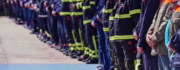 A group of firefighters lined up, saluting the flag, applauding in solidarity, and gearing up for...