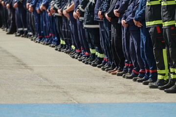 A group of firefighters lined up, saluting the flag, applauding in solidarity, and gearing up for...