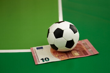 Soccer ball and 10 euro bill on a green background gkak on a corner kick, close-up, sports...