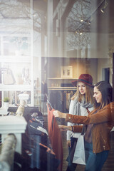 Customer, women and happy with dress in boutique store for promotion, sale and discount. Smile, female friends and people checking rack of clothes in fabric, material and retail shop at indoor mall