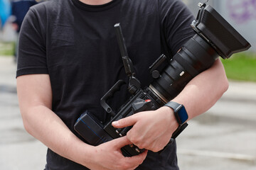 A skilled videographer, armed with professional equipment, adeptly captures outdoor events, demonstrating precision and creativity in cinematic storytelling through the lens of their camera