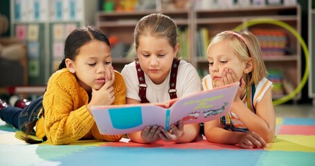 Children, book and reading together at school, learning and literacy knowledge or mind development. Girls, kids and storytelling for education, english and literature information on mat for language © N Lawrenson/peopleimages.com