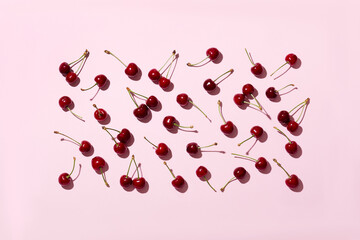 Ripe delicious cherries or sweet cherries on a pink background, hard shadows. Top view.