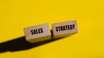 Sales strategy message written on wooden blocks with yellow background. Conceptual sales strategy symbol. Copy space.