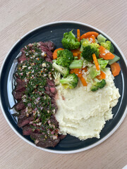 Kangaroo streak with chimichurri sauce with a side of vegetables and mashed potato.
