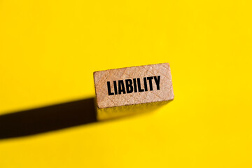 Liability message written on wooden block with yellow background. Conceptual liability word symbol....