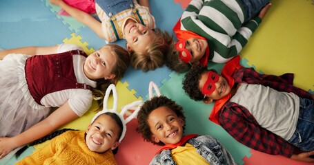 Happy children, friends and costume in class above on floor for dress up or casual day at school....