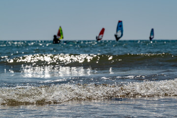 Waves of the sea with windsurfers on the background 