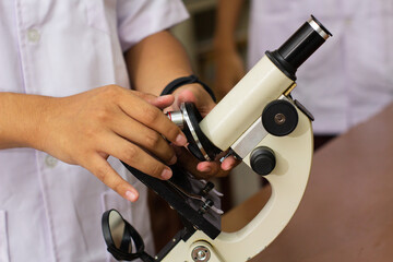 a person's hand holding a microscope in a laboratory room