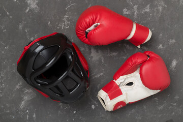 Boxing helmet and gloves on concrete background, top view.