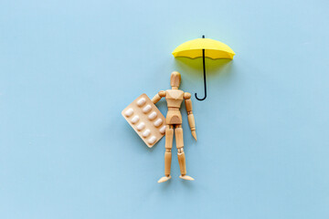 Medical insurance concept - wooden dummy man with umbrella