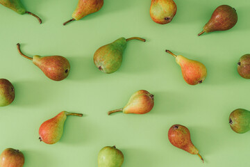 Trendy fruit pattern made of pears on pastel green background. Minimal food layout. Nature summer fruit concept. Pear aesthetic. Flat lay, top of view.