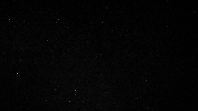 Stardust in Flight. Slow Motion. Bright white particles move slowly and erratically in the dark