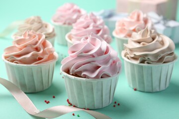 Delicious birthday cupcakes, ribbon and sprinkles on turquoise background, closeup