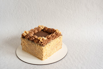 Square cake decorated with buttercream and nuts on a gray background. Homemade sponge cake.   Side view of a plain white decorated cake.  Mocap. Place for the inscription. 