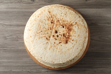 Many tasty homemade tortillas on wooden table, top view