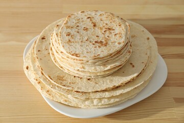 Many tasty homemade tortillas on wooden table