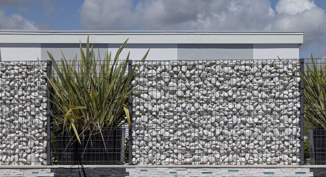 Brise-vue en gabions de galets blancs en aluminium d'une maison	