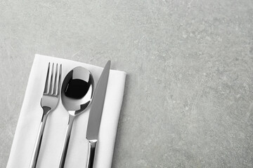 Stylish cutlery set and napkin on grey table, top view. Space for text