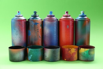 Many spray paint cans with caps on green background