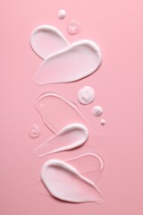 Samples of face cream on pink background, top view
