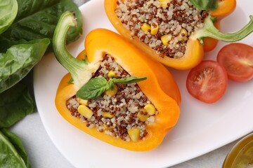 Quinoa stuffed bell pepper with basil and tomato on light table, top view