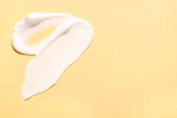 Samples of face cream on pale yellow background, top view. Space for text