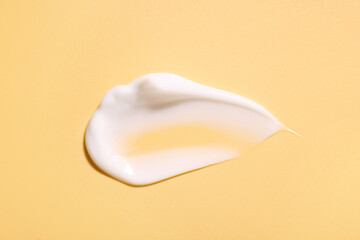 Sample of face cream on pale yellow background, top view