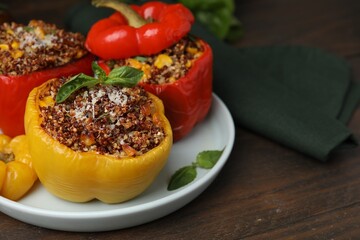 Quinoa stuffed peppers with corn and basil on wooden table, closeup. Space for text