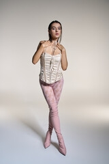 Young woman with wet hair wearing stylish pink pants and a white corset.