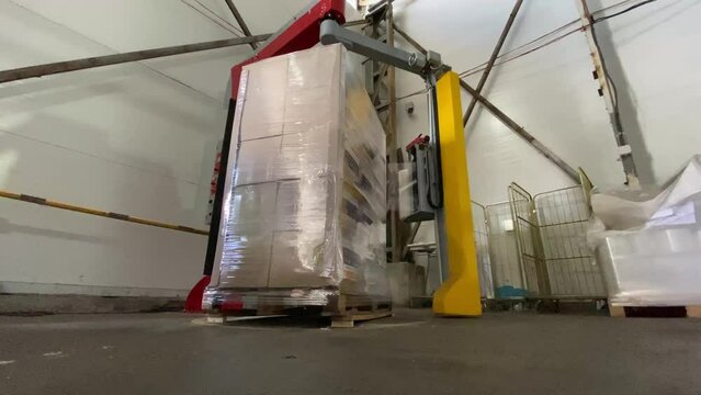 The boxes on the pallet are wrapped with film. Equipment for packing large pallets. Oilcloth packaging of humanitarian aid packages in Ukraine. High quality 4k video