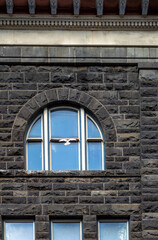 Arched Window in a Black and Brown Stone Block Building.