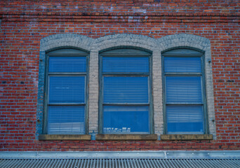 Three Arched Windows with White Facade on a Red Brick Building.