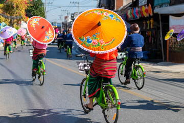 Fototapeta premium Men and women holding beautiful umbrellas and cycling Performances at the Bo Sang Umbrella Festival, Chiang Mai, Thailand