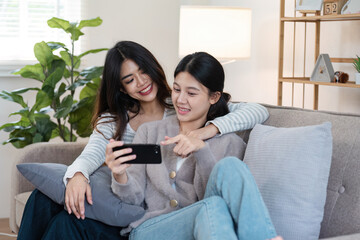 Obraz premium Happy woman lesbian gay lgbt couple enjoying fun gaming session on the couch at home. lgbt concept