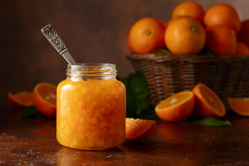Orange jam and fresh fruits on a brown vintage table.