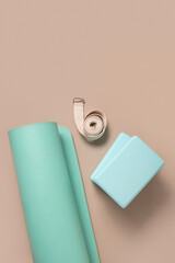 Green yoga blocks and white strap on beige background. Yoga practice, relaxation and meditation concept. Top view with copy space. Vertical format.