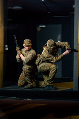 At a professional shooting range two military trainers perform tactical exercises with pistols