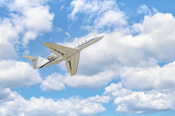 Private business plane flying under a blue sky with white clouds	