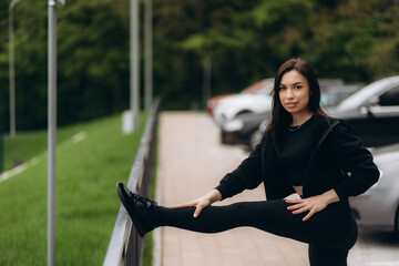 view on woman warming up her muscles and leans with one foot on the fence while stretching the other leg. Copy space