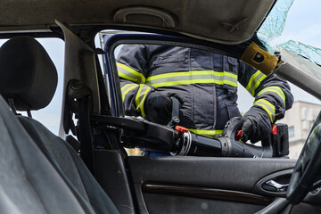 A dedicated team of professional firefighters employs specialized tools to cut and break through vehicle wreckage, showcasing their skilled collaboration and swift response in rescuing individuals