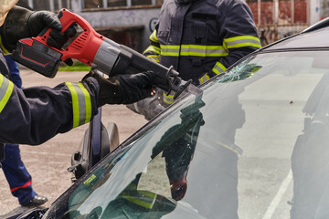 Naklejka premium A dedicated team of professional firefighters employs specialized tools to cut and break through vehicle wreckage, showcasing their skilled collaboration and swift response in rescuing individuals